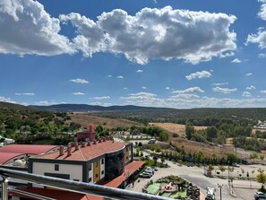 A view of a building with a red roof, a parking area, and a landscape with hills and trees. - Tokat Termal Kaplıcaları (Sulusaray)