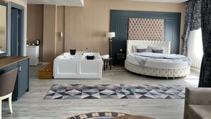 A modern hotel room with a round bed, a separate bathroom with a bathtub, a desk, and a chair. - Tokat Termal Kaplıcaları (Sulusaray)