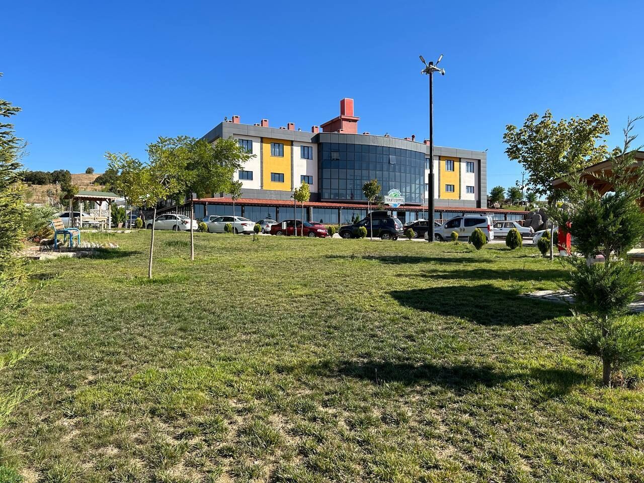A modern building with a flat roof, large windows, and a parking lot in front.