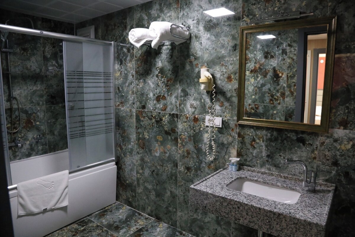 A bathroom with a shower, a sink, a towel rack, and a mirror.