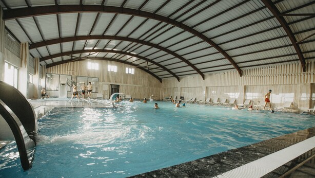 An indoor swimming pool with a high ceiling and a curved roof structure. - Tokat Termal Kaplıcaları (Sulusaray)