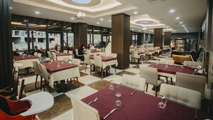 A modern restaurant with checkered flooring, marble-topped tables, and a mix of white and red tablecloths. - Tokat Termal Kaplıcaları (Sulusaray)