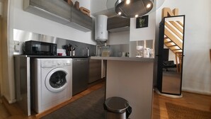 A compact kitchen with a washing machine, microwave, and a small island with a sink.