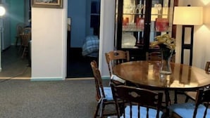 A dining area with a round table, six wooden chairs, a glass cabinet with glassware, and a lamp. - Close to JFK and Laguardia Air ports (Queens)