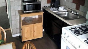 A compact kitchen with wooden cabinets, a microwave, a toaster, a coffee maker, and a gas stove. - Close to JFK and Laguardia Air ports (Queens)