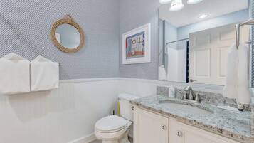 Un bagno con servizi igienici, lavandino e specchio. C'è un porta asciugamani con asciugamani, un quadro appeso al muro e una parete strutturata.