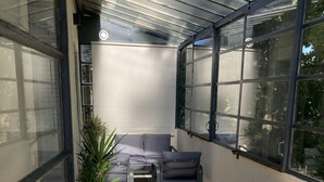 Une pièce baignée de lumière, avec une table et des chaises en bois, un canapé gris et une plante en pot.