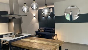 Une cuisine moderne avec une table à manger en bois, des chaises noires et des luminaires suspendus.
