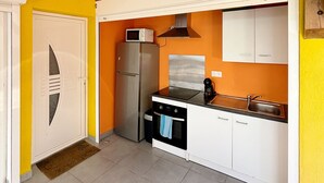 Une cuisine de taille réduite équipée d’un réfrigérateur, d’un four à micro-ondes, d’une cuisinière et d’un évier.