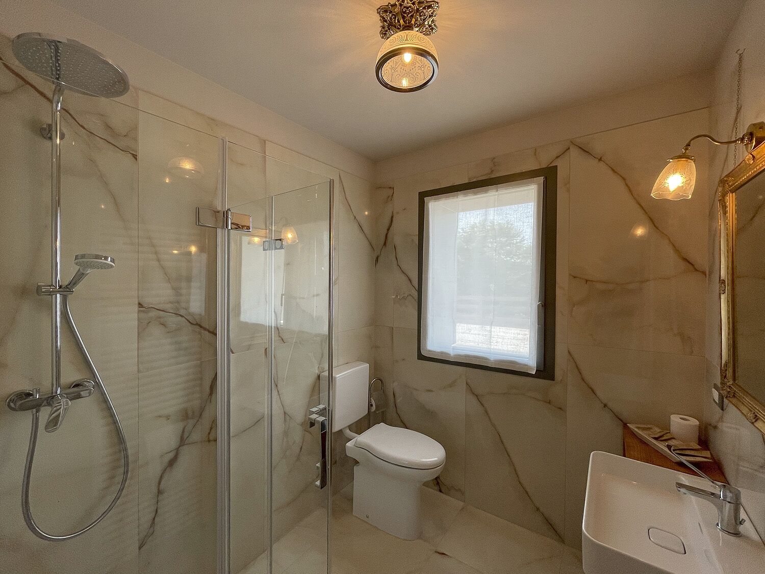 Une salle de bain avec une douche à parois de verre, des toilettes, un lavabo et une fenêtre.