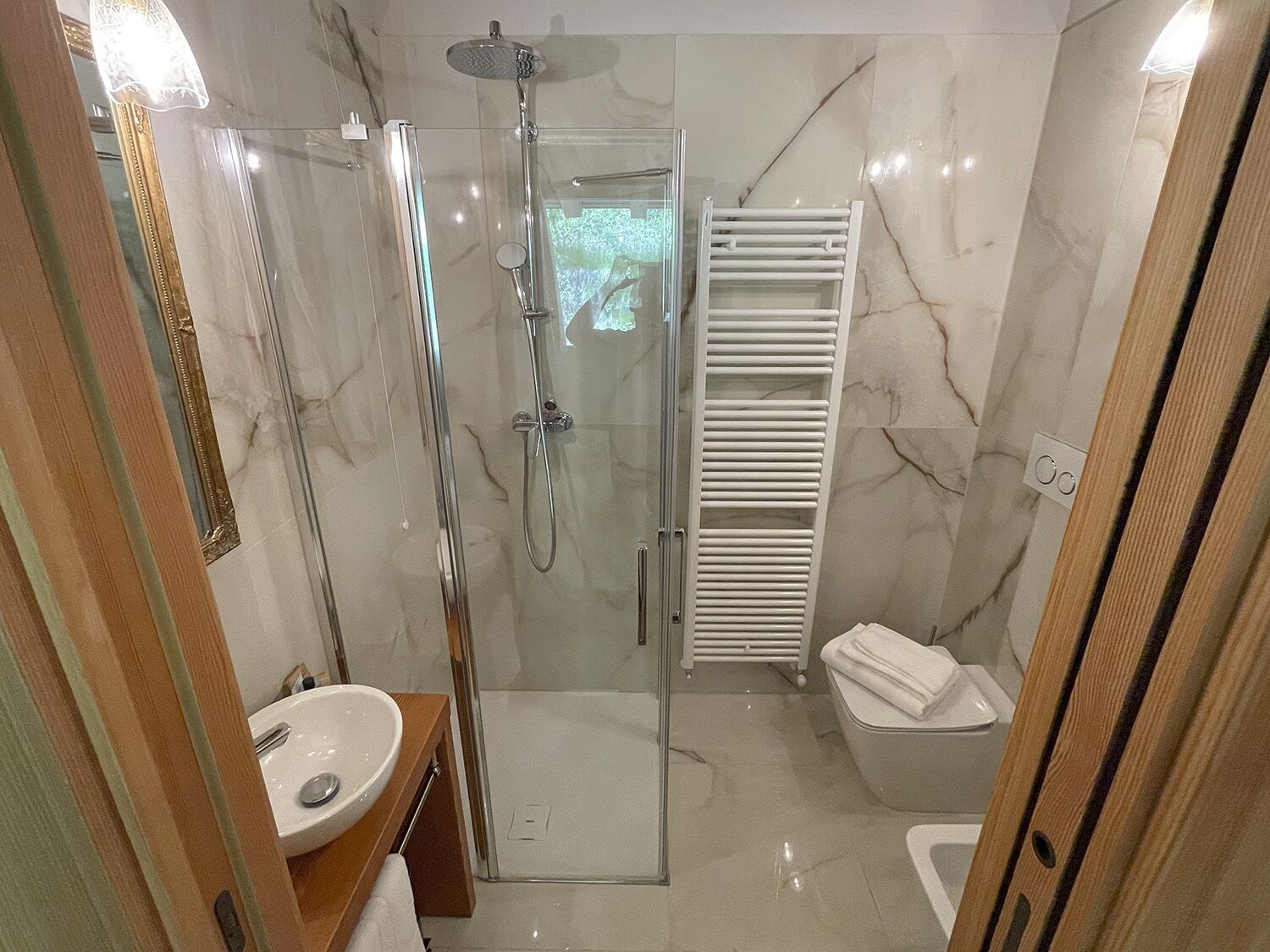 Un baño moderno con ducha envuelta en vidrio, un lavamanos blanco y un inodoro blanco.