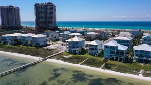 Uma área residencial costeira com propriedades na orla marítima, um píer e uma vista clara do oceano.