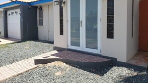 Un edifici residencial amb una porta blanca, una porta de garatge i un teulat blau.