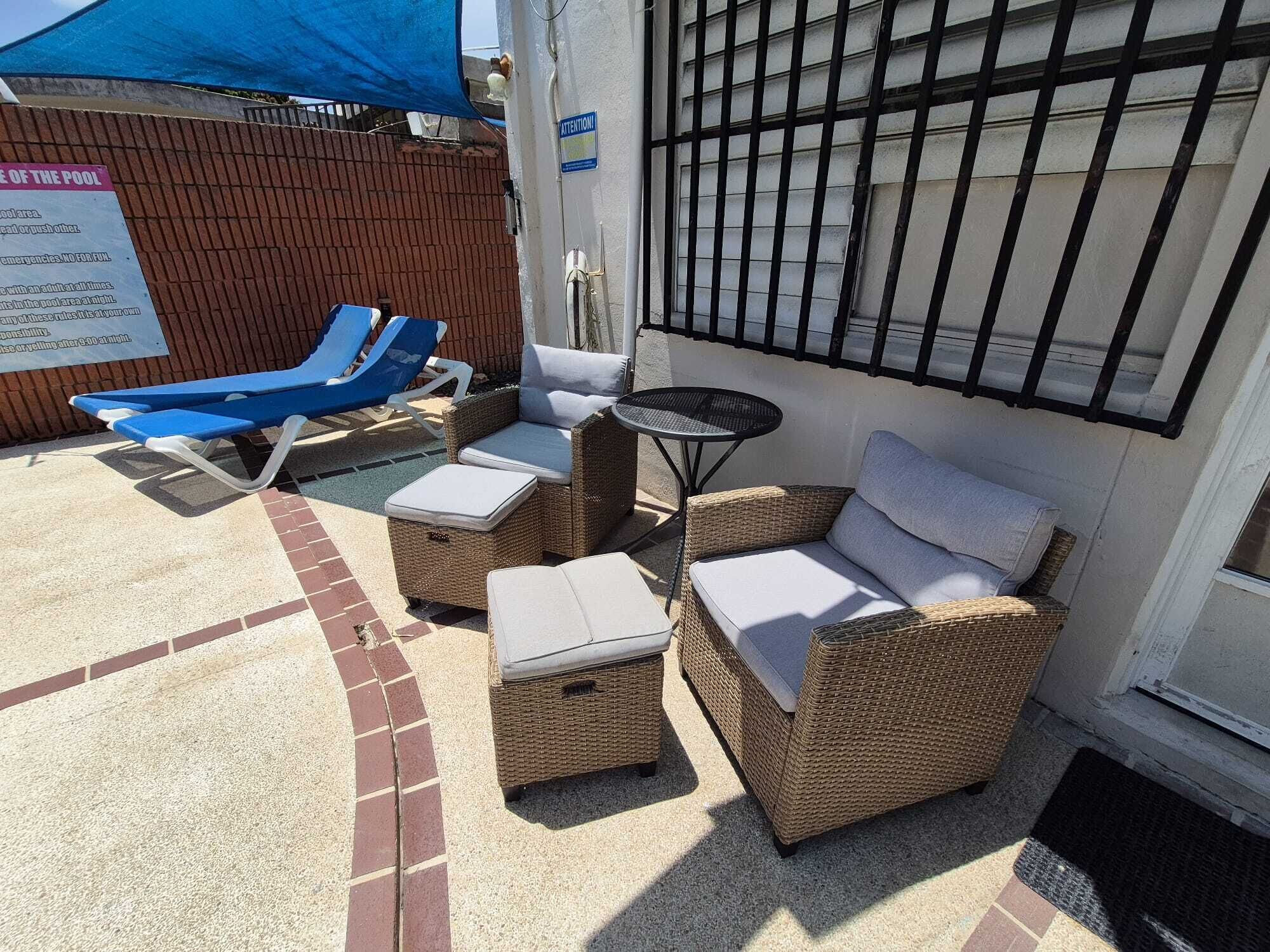An outdoor seating area with wicker furniture and a blue umbrella.