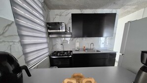Cuina moderna amb fogó a gas, rentatallops i armaris negres. Hi ha un televisor de pantalla plana muntat sobre el fogó.