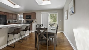 A modern kitchen with a large island, wooden cabinets, and a dining area with a table set for four.