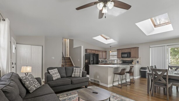 A modern living room with a sofa, coffee table, and a dining area with chairs and a table.