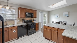 A modern kitchen with wooden cabinets, a granite countertop, a built-in microwave, and a gas stove.