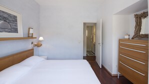 Un dormitorio con cama, cómoda, espejo y un pasillo que conduce a un baño.