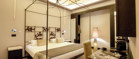 A modern hotel room with a large bed, bedside table, lamp, and a mirror.