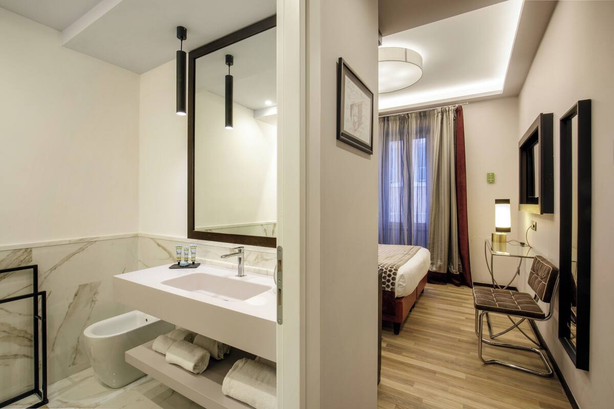 Ein modernes Badezimmer in einem Hotel mit einem großen Spiegel, einem Waschbecken und einem Bidet.