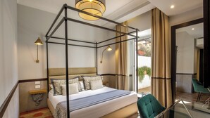 Une chambre moderne avec un lit à baldaquin, une table en verre et un fauteuil vert.