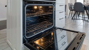 Una cocina moderna con horno integrado, luces colgantes y una zona de comedor con sillas.