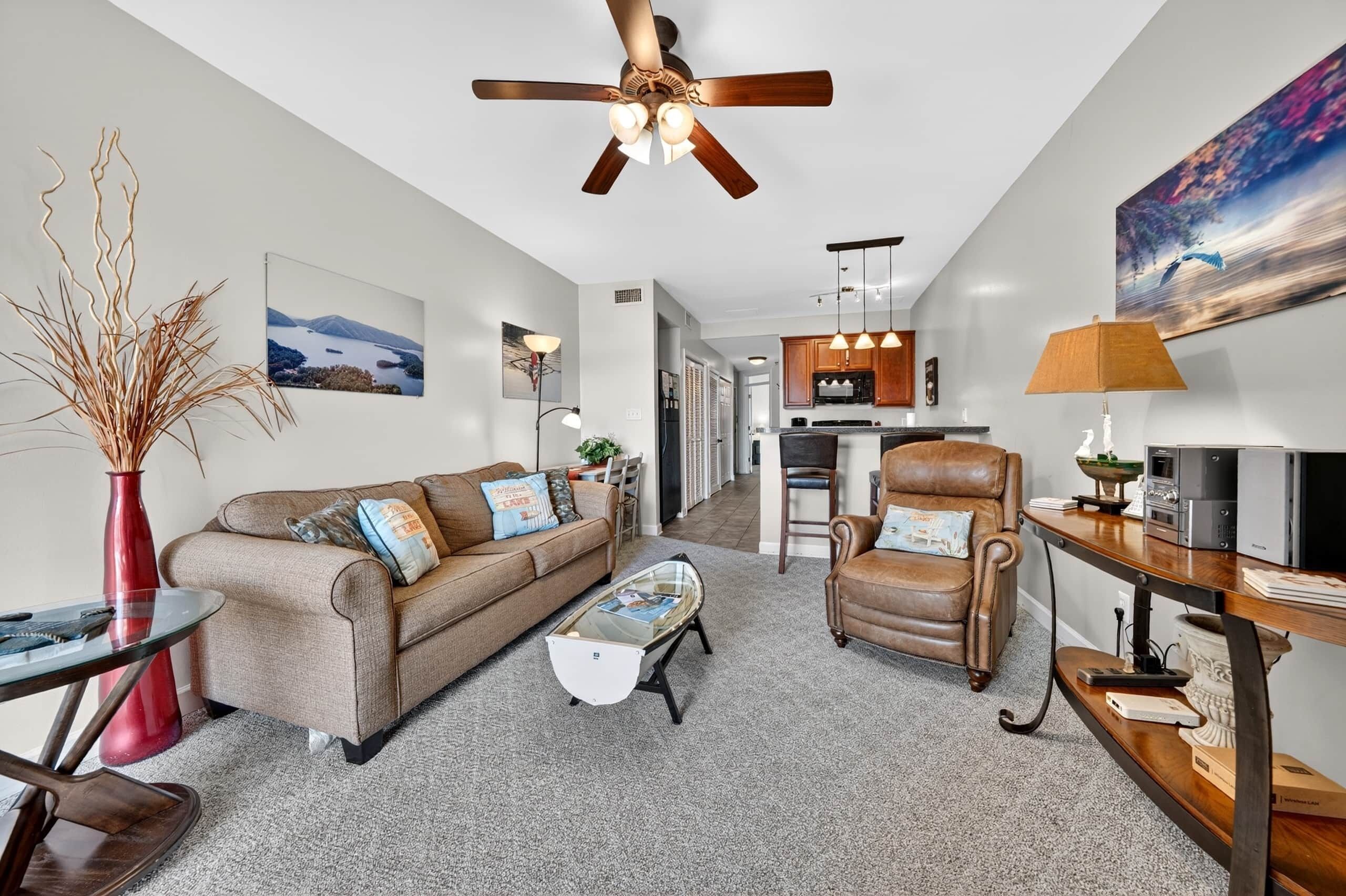 A modern living room with a sofa, armchair, coffee table, and a dining area with a table and chairs.