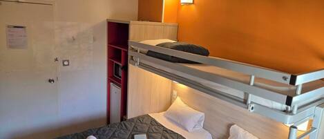 Habitación de hotel con dos camas, un armario y un escritorio pequeño.