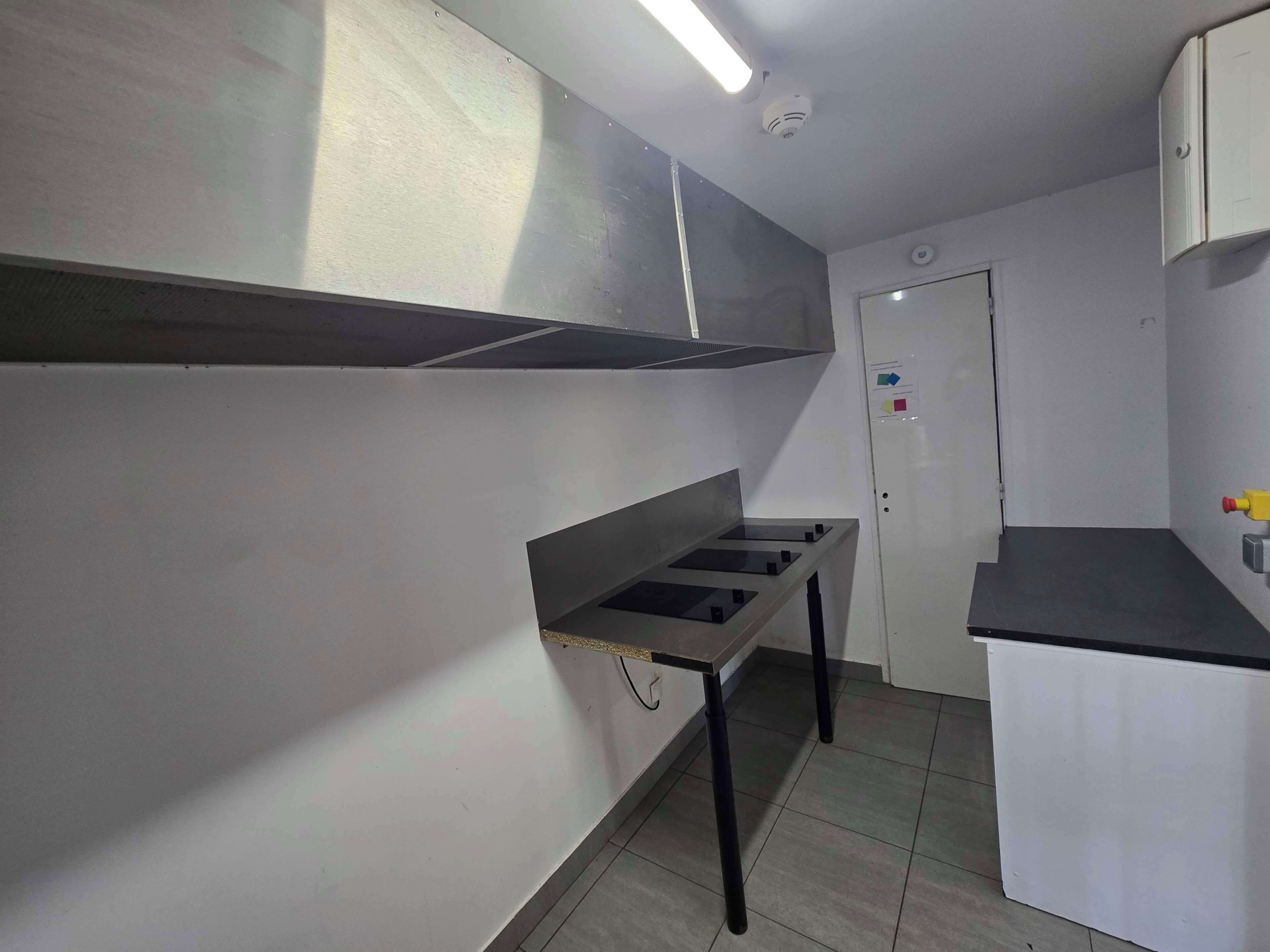 Una cocina con una campana extractora de acero inoxidable, un fregadero y un armario blanco.