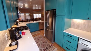 A modern kitchen with teal cabinets, stainless steel appliances, and a white countertop. - Quiet retreat near Plaza (Santa Fe)