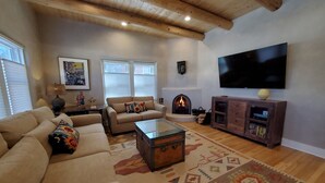 A living room with a sofa, a coffee table, a fireplace, a TV, and a wooden cabinet. - Quiet retreat near Plaza (Santa Fe)