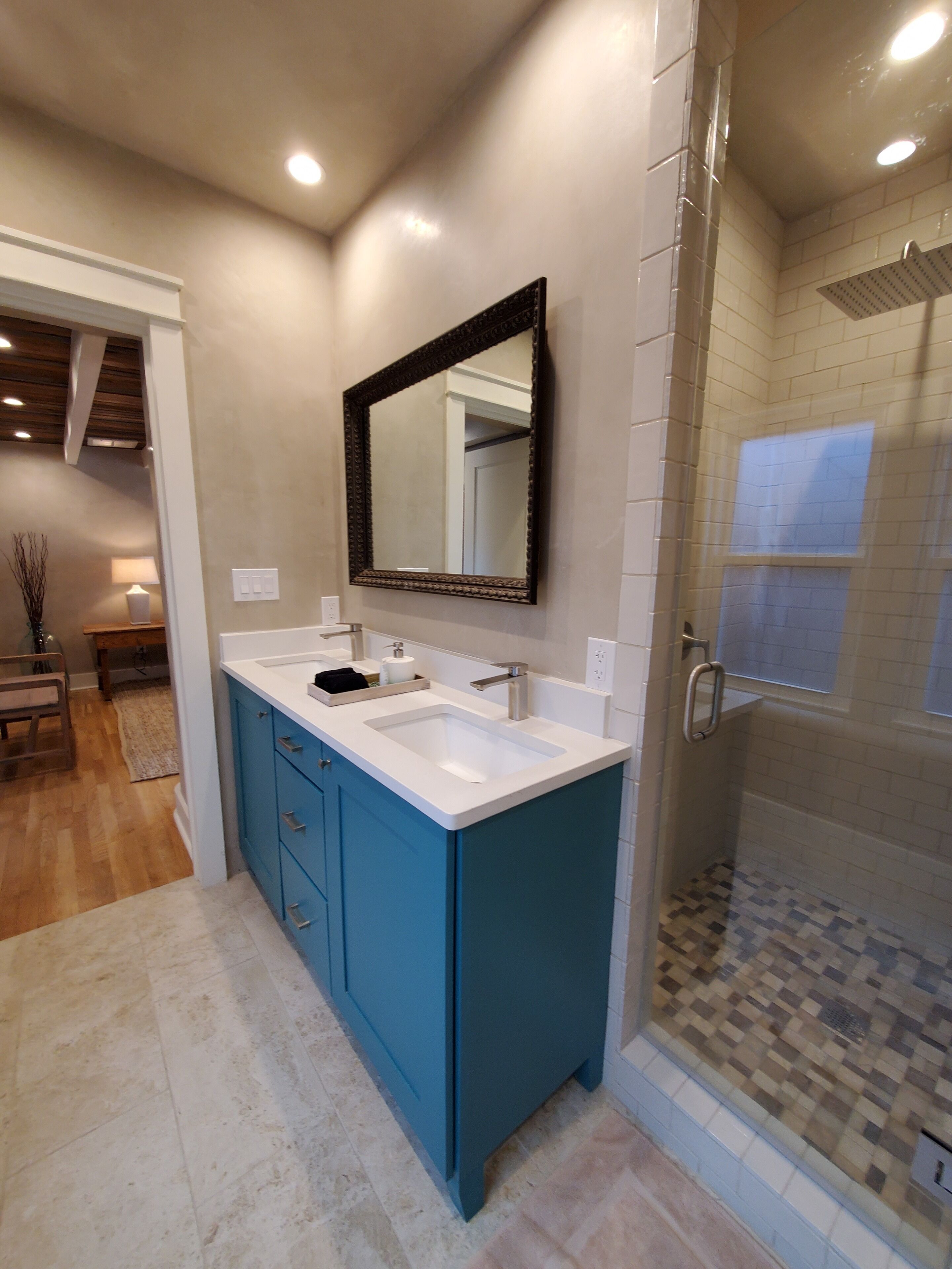 A bathroom with a large mirror, two sinks, and a shower area.