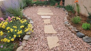 A garden pathway with stepping stones, surrounded by various plants and flowers. - Quiet retreat near Plaza (Santa Fe)