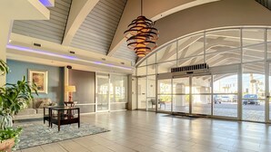 A spacious lobby with a modern design, featuring a large glass door entrance, a contemporary light fixture, and a seating area with a table and chairs. - Beachfront Studio - Sleeps 4 (Daytona Beach)