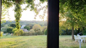 A view through a window of a grassy area with trees and a white table and chairs. - Villa des oliviers ideal for visiting Provence (Caumont-sur-Durance)