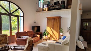 A spacious living room with a large window, a television, a wooden cabinet, and a sofa. - Villa des oliviers ideal for visiting Provence (Caumont-sur-Durance)