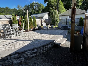 Un patio con suelo de piedra, mobiliario exterior y una pared de piedra.