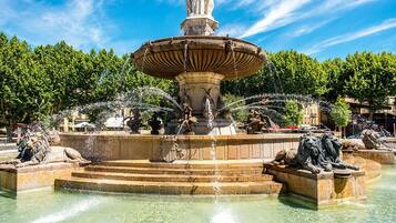 Una fontana classica con una statua al centro, circondata da leoni di pietra e scalini che portano all'acqua.