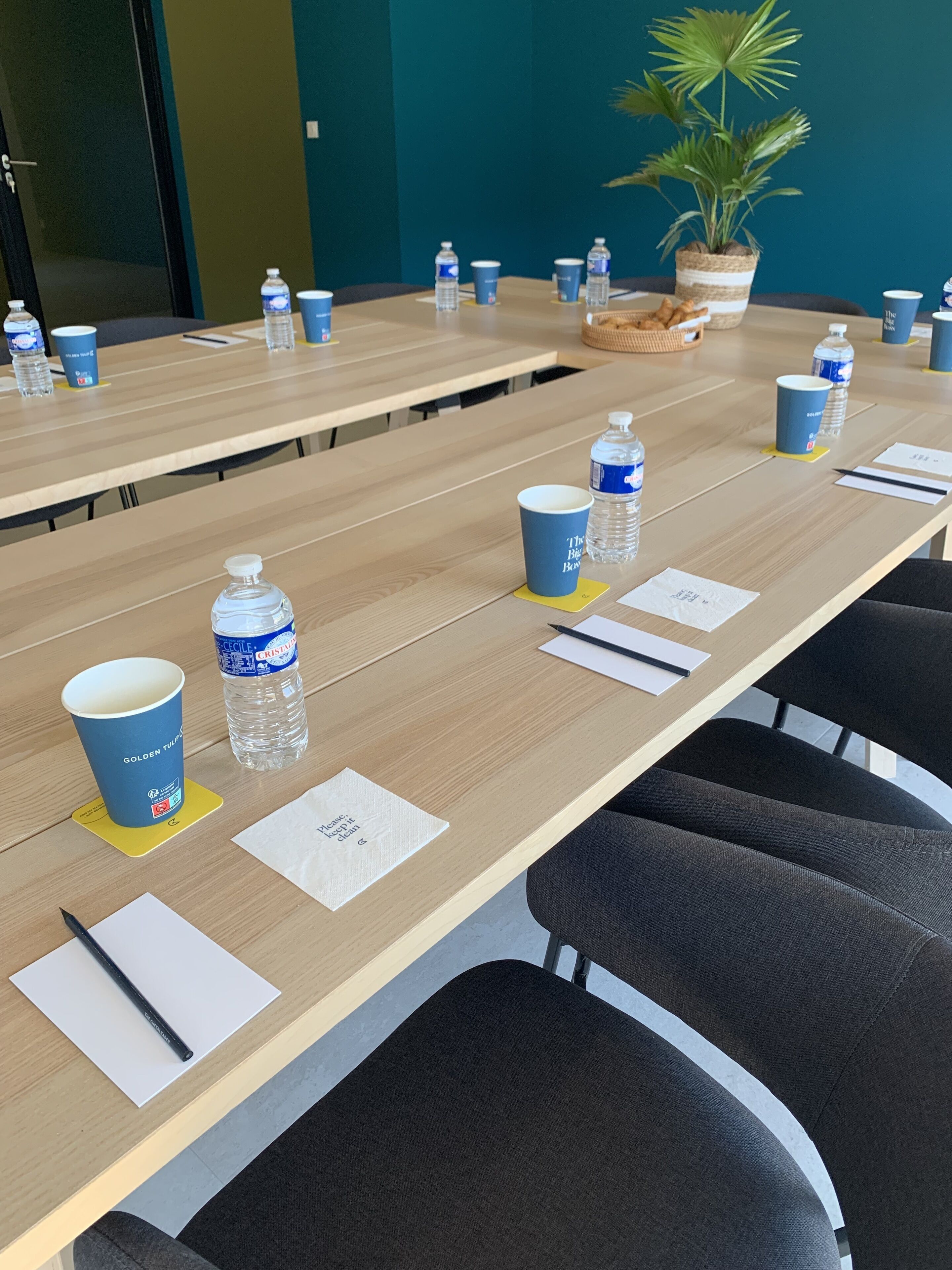 A conference room with a long table, water bottles, and cups.