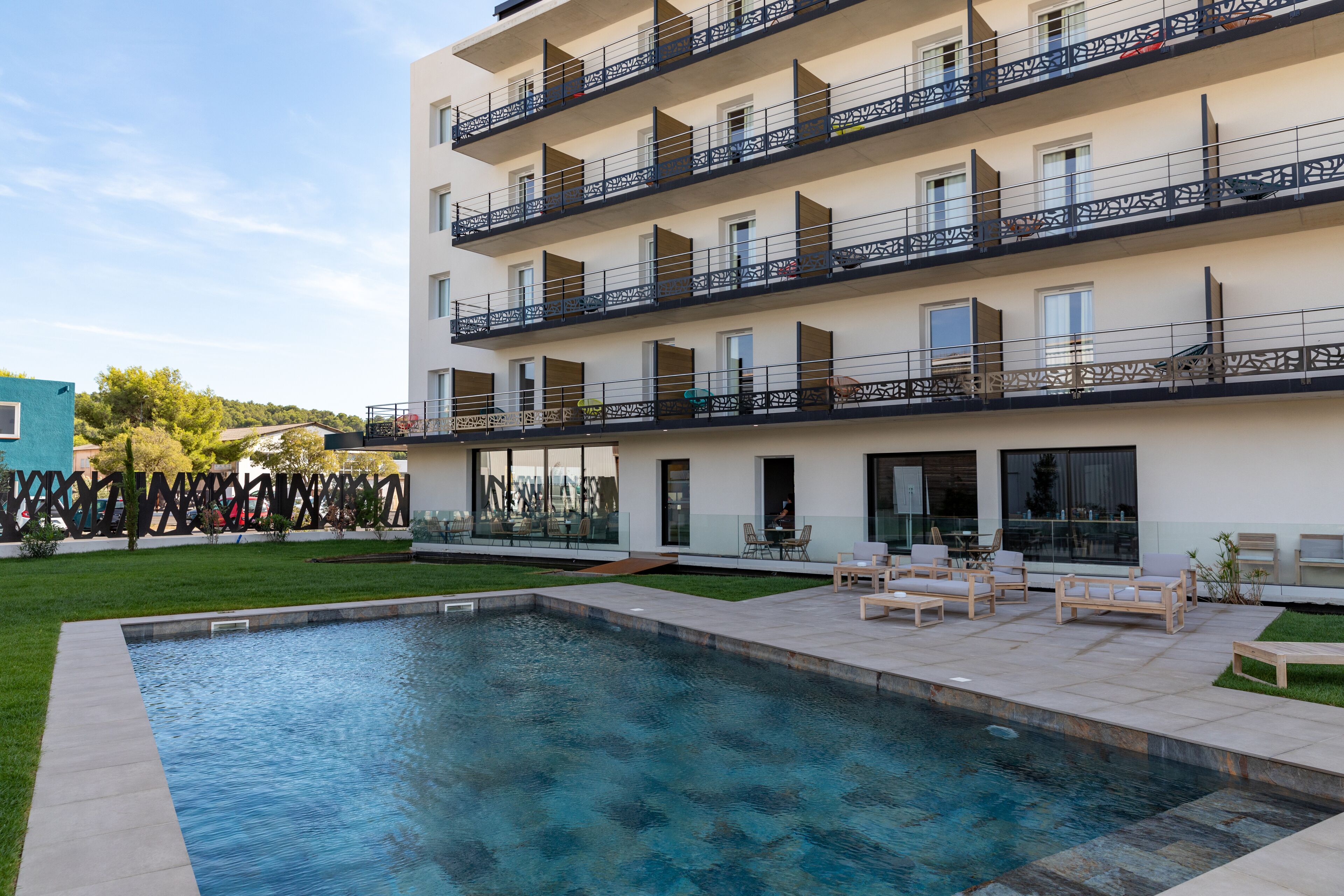 A modern multi-story building with a swimming pool and outdoor seating area.