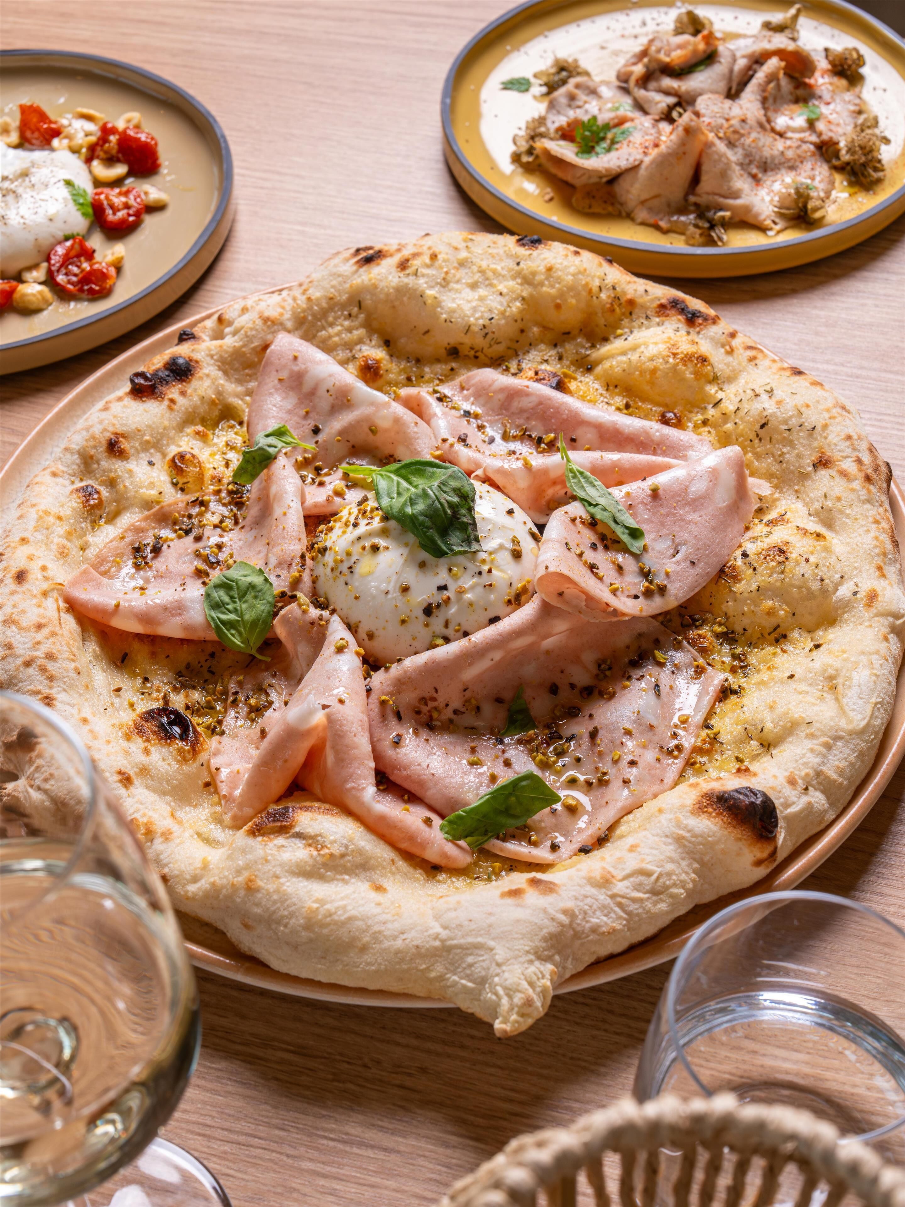 A pizza with ham and cheese on a wooden table.
