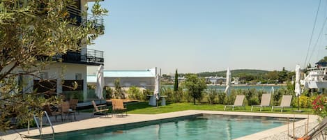 Piscina con sillas de descanso y vista a un cuerpo de agua.