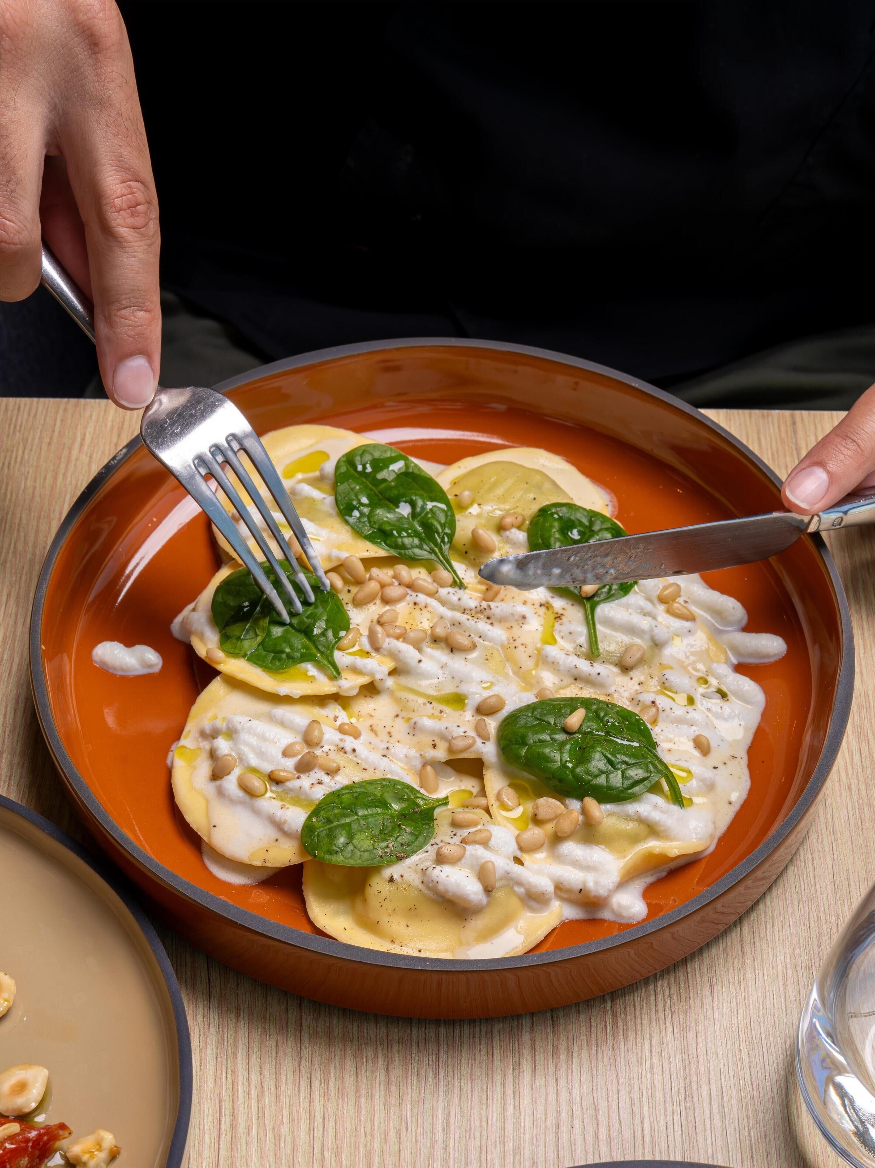 A plate of ravioli with spinach and pine nuts.