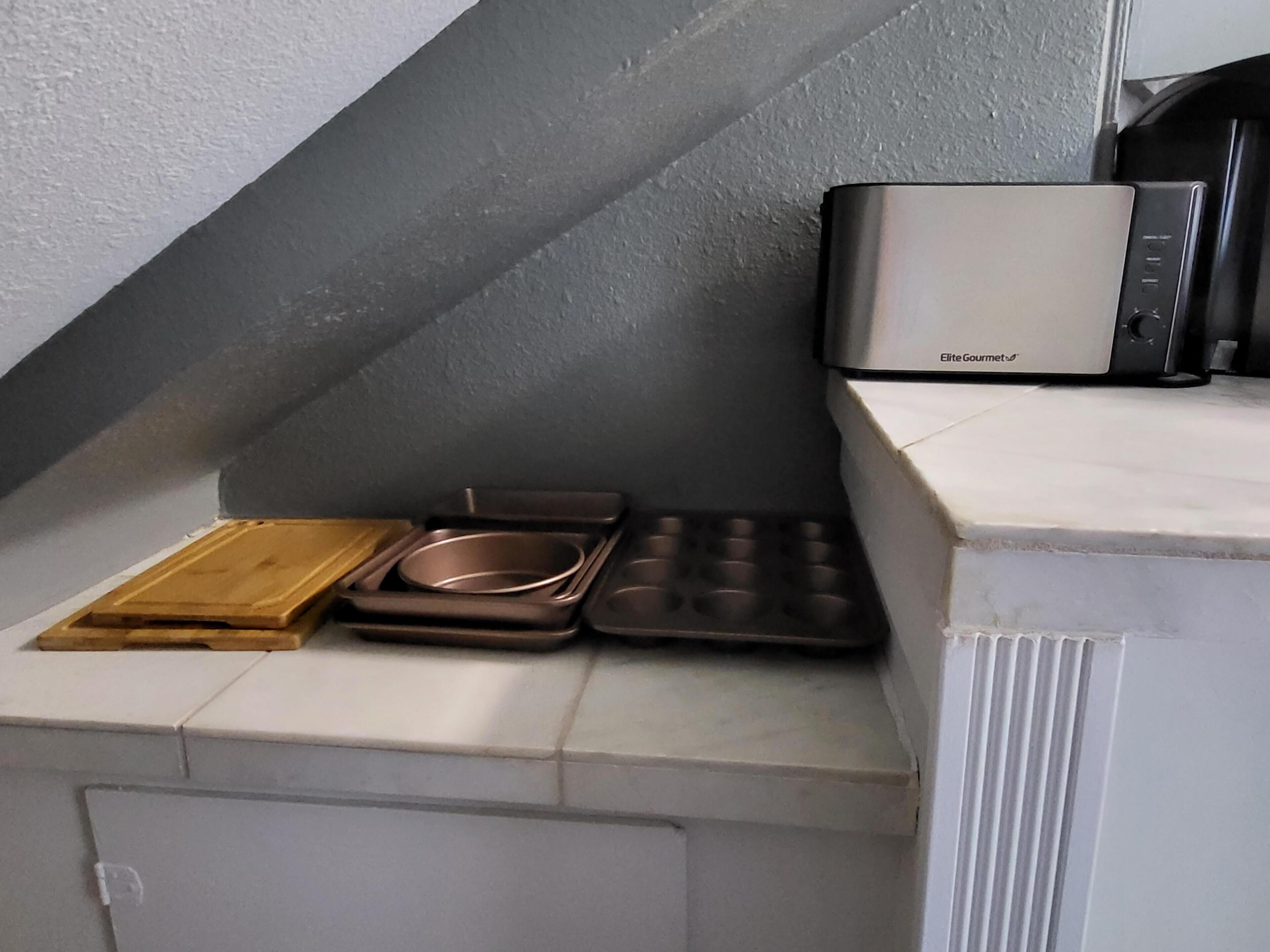 A kitchen with a microwave, a cutting board, and a baking tray.