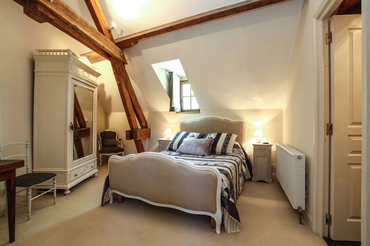 A bedroom with a large bed, a wardrobe, a desk, and a radiator.