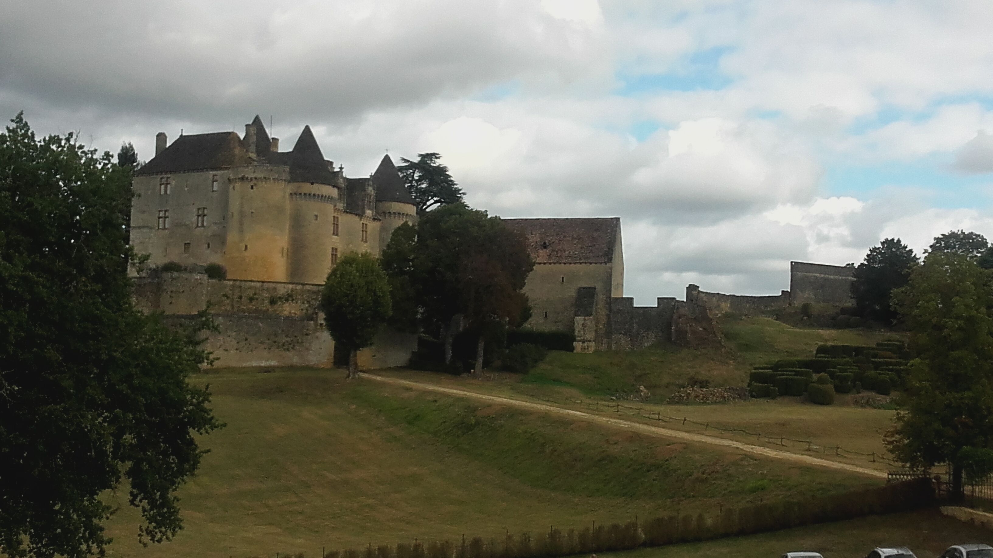 A historic castle with a fortified wall, a central tower, and a surrounding moat.