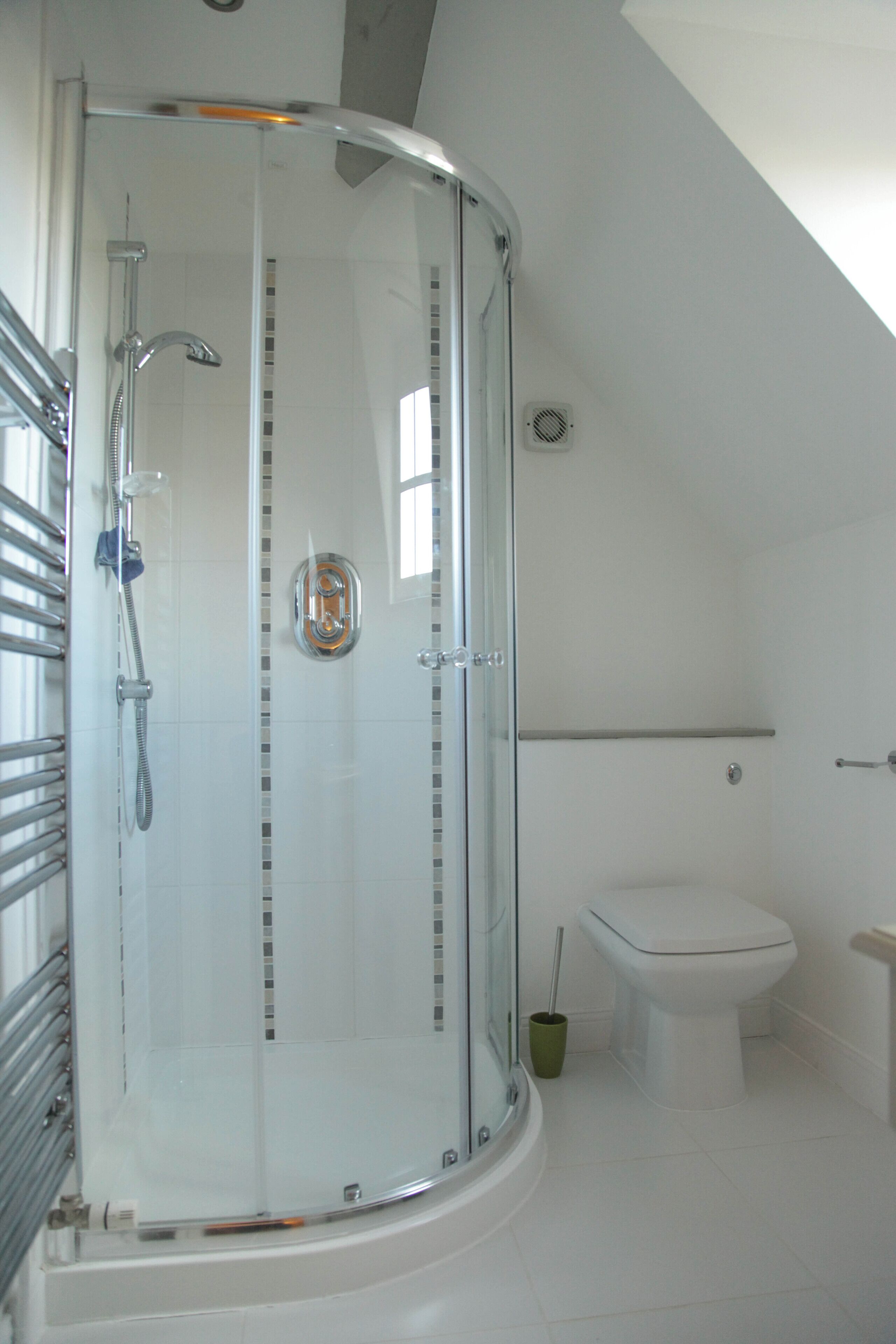 A modern bathroom with a glass-enclosed shower, a toilet, and a small sink.