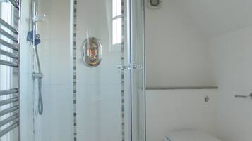 Een moderne badkamer met een douchecabine van glas, een toilet en een klein wastafeltje.