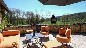 An outdoor patio with seating and a table, overlooking a scenic landscape.